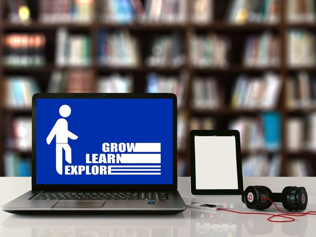 A computer displaying a graphic with the words grow, learn, explore as steps for a stick figure.