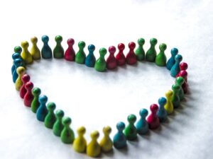 Diversity and harmony represented by different color wooden pawns put in a heart shape.